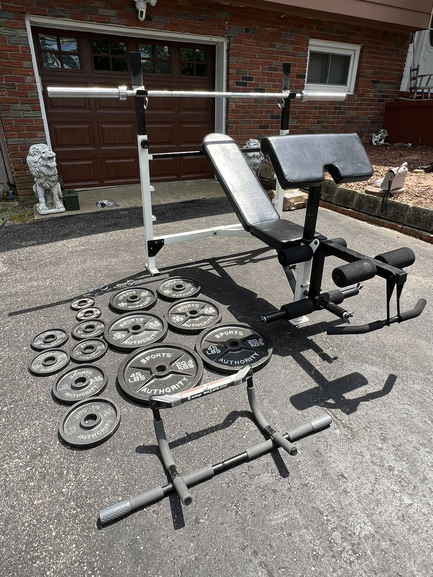 Complete gym set up with adjustable bench press, weight set, barbell, pull up bar, and ab roller