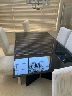 Glass dining room table with six fabric chairs in an entryway table