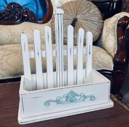Shabby chic picket fence organizer is a wooden display box featuring a distressed white finish and a light blue accent detail.