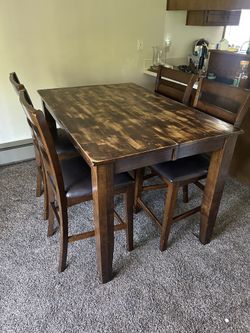 Real wood dining room table with four padded chairs and extendable leaf built-in