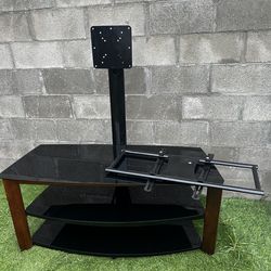 black tempered glass TV stand with three shelves and an integrated mounting bracket