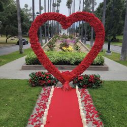 Silk Flower Heart Arch with a Flower Bouquet, Petals on the floor, carpet, and candles on the floor.