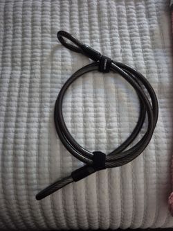 NEW black Titanker Coiled Cable Lock featuring a flexible steel cable with a protective vinyl coating and a branded velcro strap.