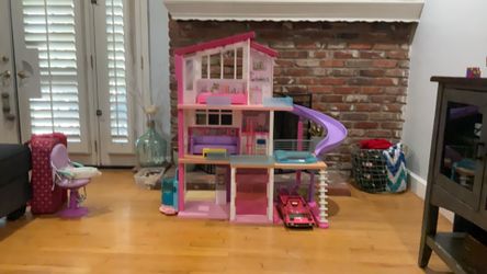 Barbie dream house with dolls, clothes, and a toy car