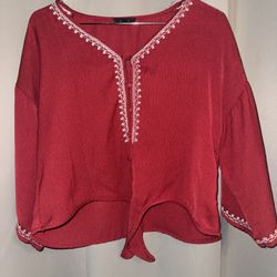 red long-sleeved tie-front top with white embroidery.