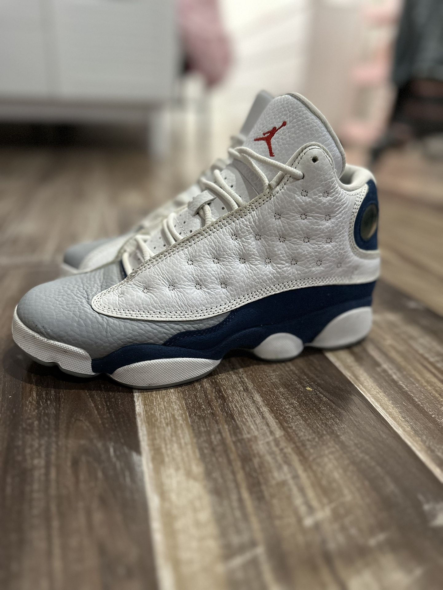 Air Jordan 13s in the “Flint” colorway (white, navy blue, and gray).
