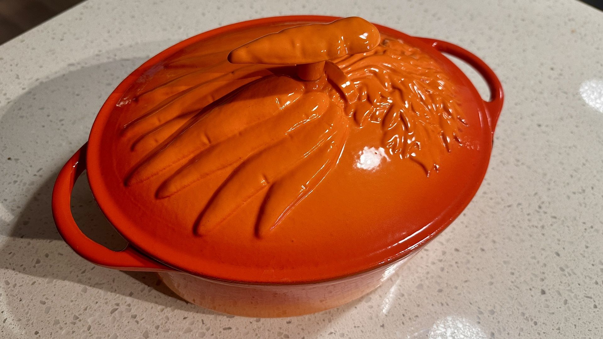 Technique enameled oval cast iron dutch oven with lid. Red Orange in color with carrot handle and lid. In very good condition. A few chips in the enam