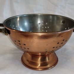 Antique copper colander with sturdy handles. Perfect for kitchen use or decor.
