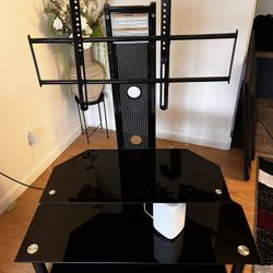 Nice 3 Tier Black Tempered Glass TV Stand with Adjustable TV Mount.  Holding a 55” Tv in pictures.  Great Like New Condition. No Scratches or Cracks. 