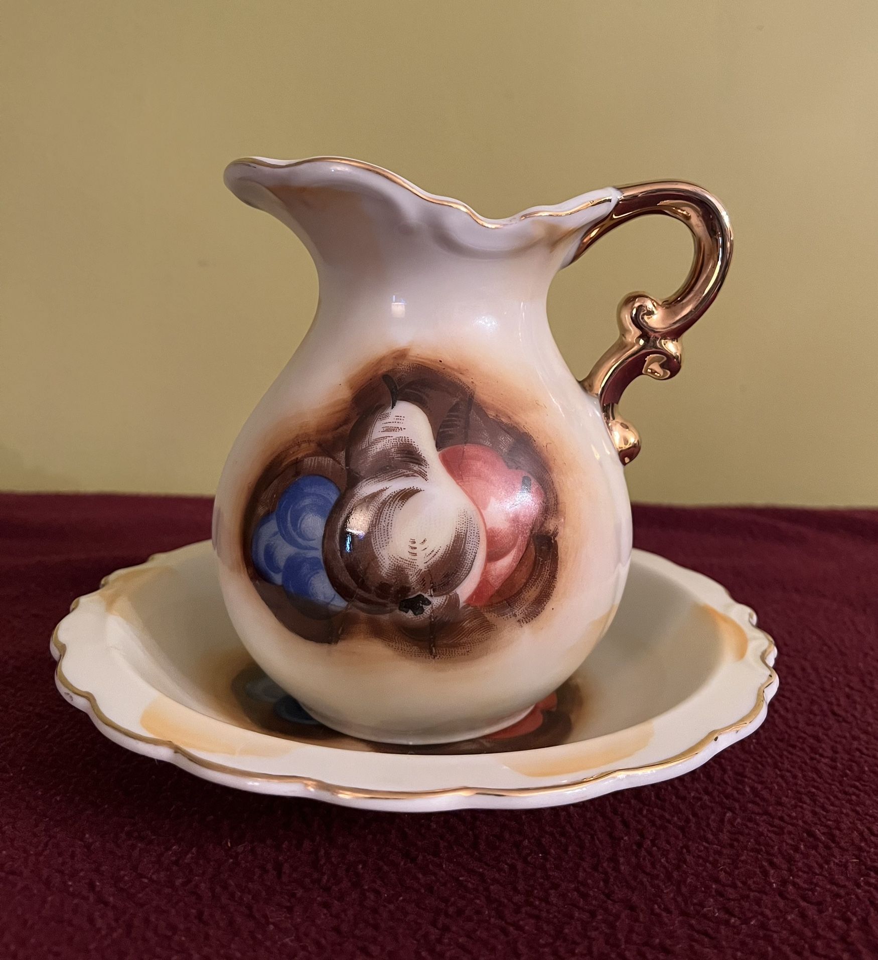 Vintage Artmark miniature porcelain pitcher and basin bowl set, hand-painted with a fruit motif and featuring gold trim.