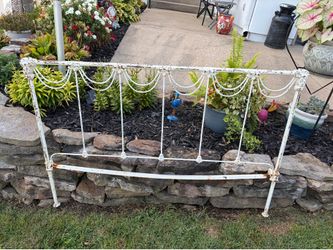 Vintage white cast iron bed frame with ornate swag and tassel.
