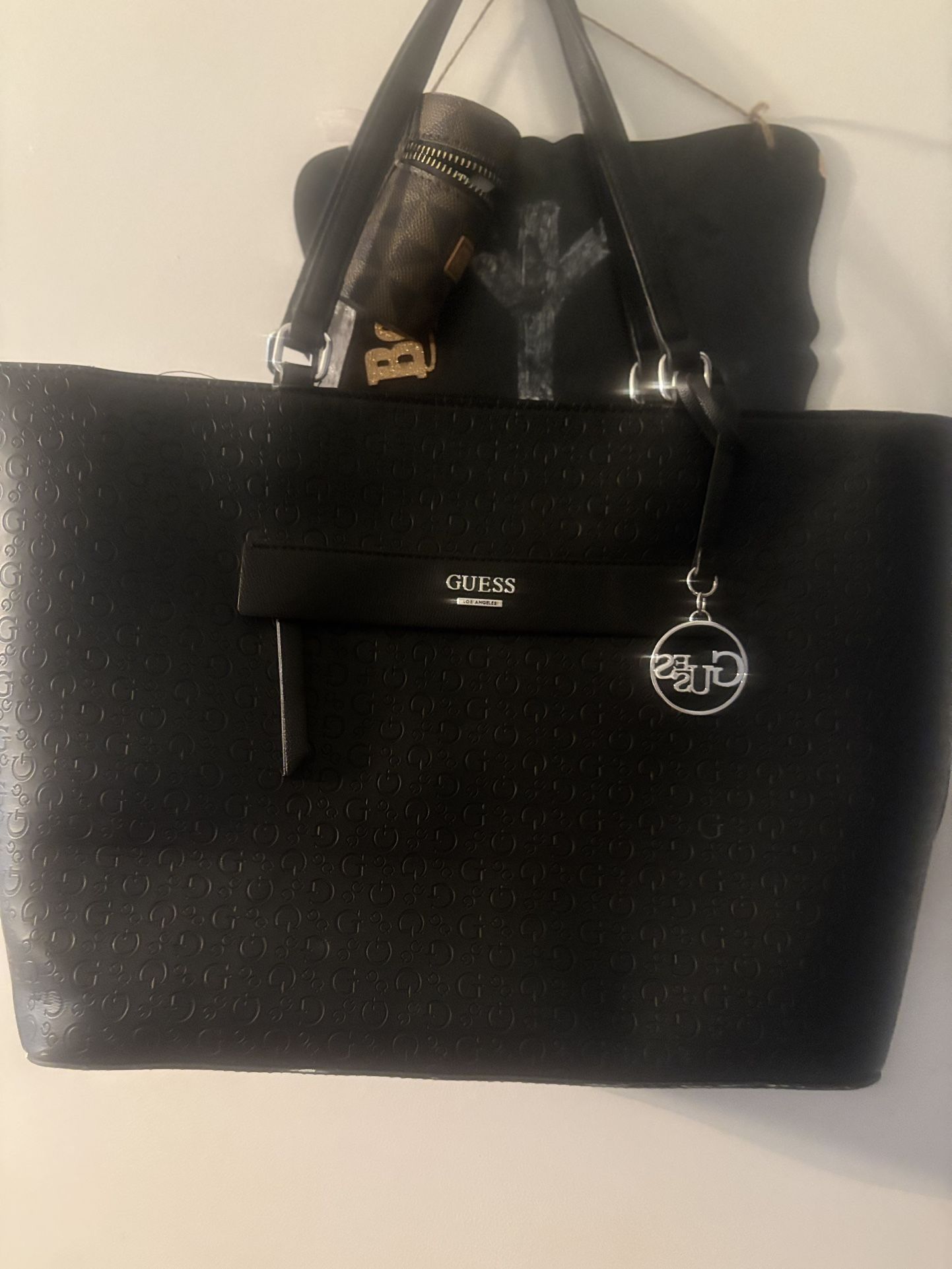 Stylish New Guess black tote bag with logo charm.
