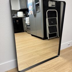 Black rounded frame bedroom/living room mirror (has small dent) - 36” x 30”