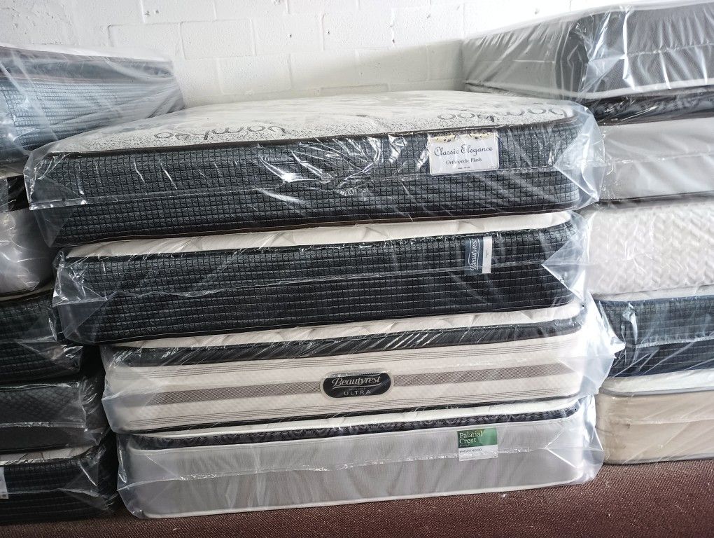 Have All Size Available Good Prices Todos Los tamaños Disponibles Stack of new mattresses wrapped in protective plastic. Multiple styles available.