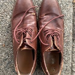 Brown leather or vinyl lace-up shoes, size 12, with some wear or peeling of the surface on the top. 