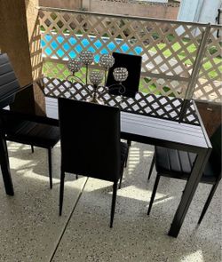 Glass dining table with four leather chairs.