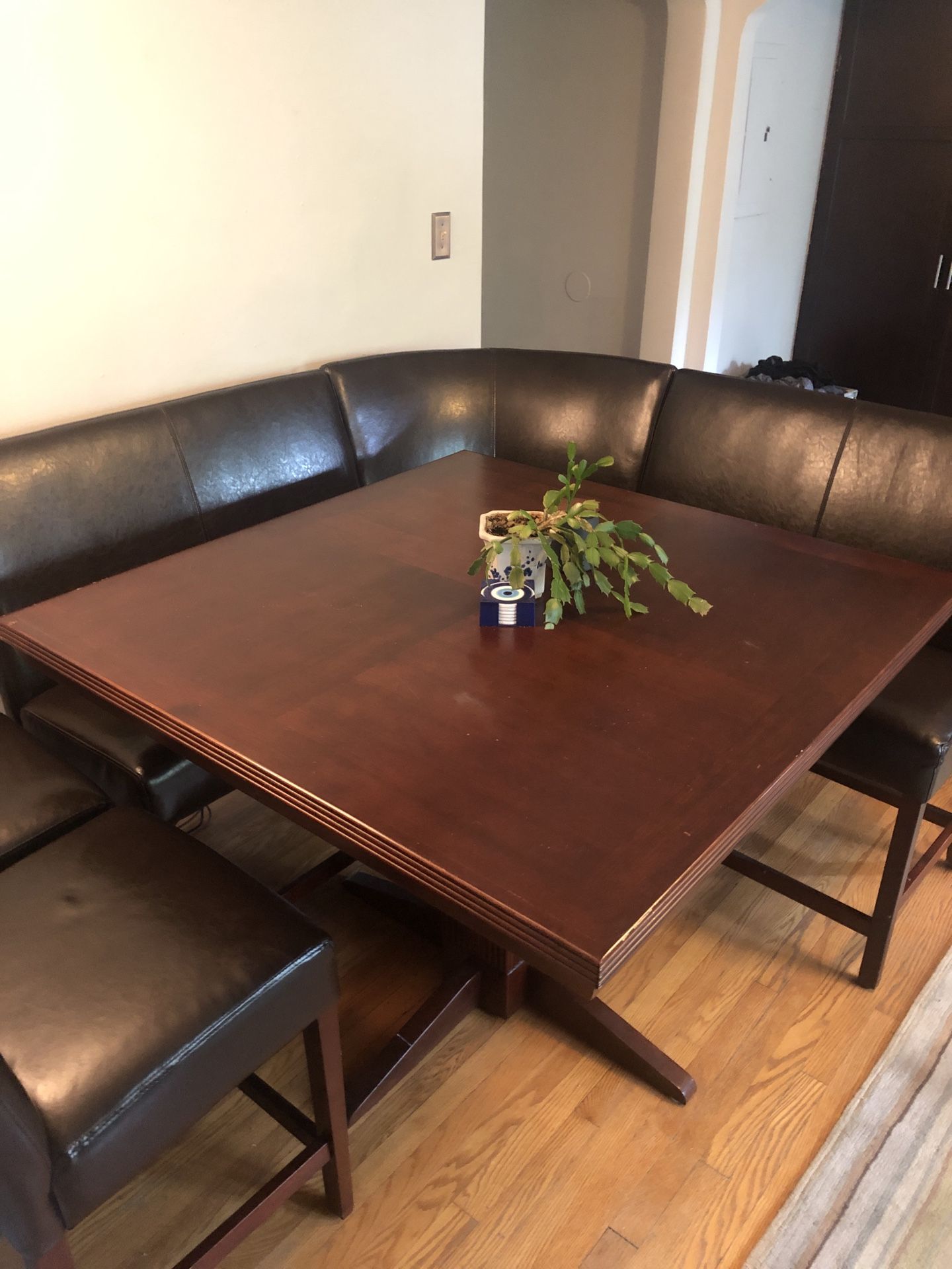 Brown square wooden table with 5 brown leather chairs