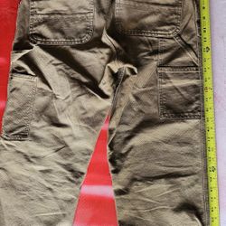 Carhartt carpenter-style work pants in a classic tan or "Carhartt Brown" color. 
30x30features visible include the signature back pocket logo, hammer 