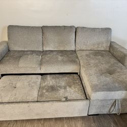 Light gray sectional couch with right-side chaise. Chaise has hidden storage and the main cushions pull out for a sleeper-style bed. Middle backrest f