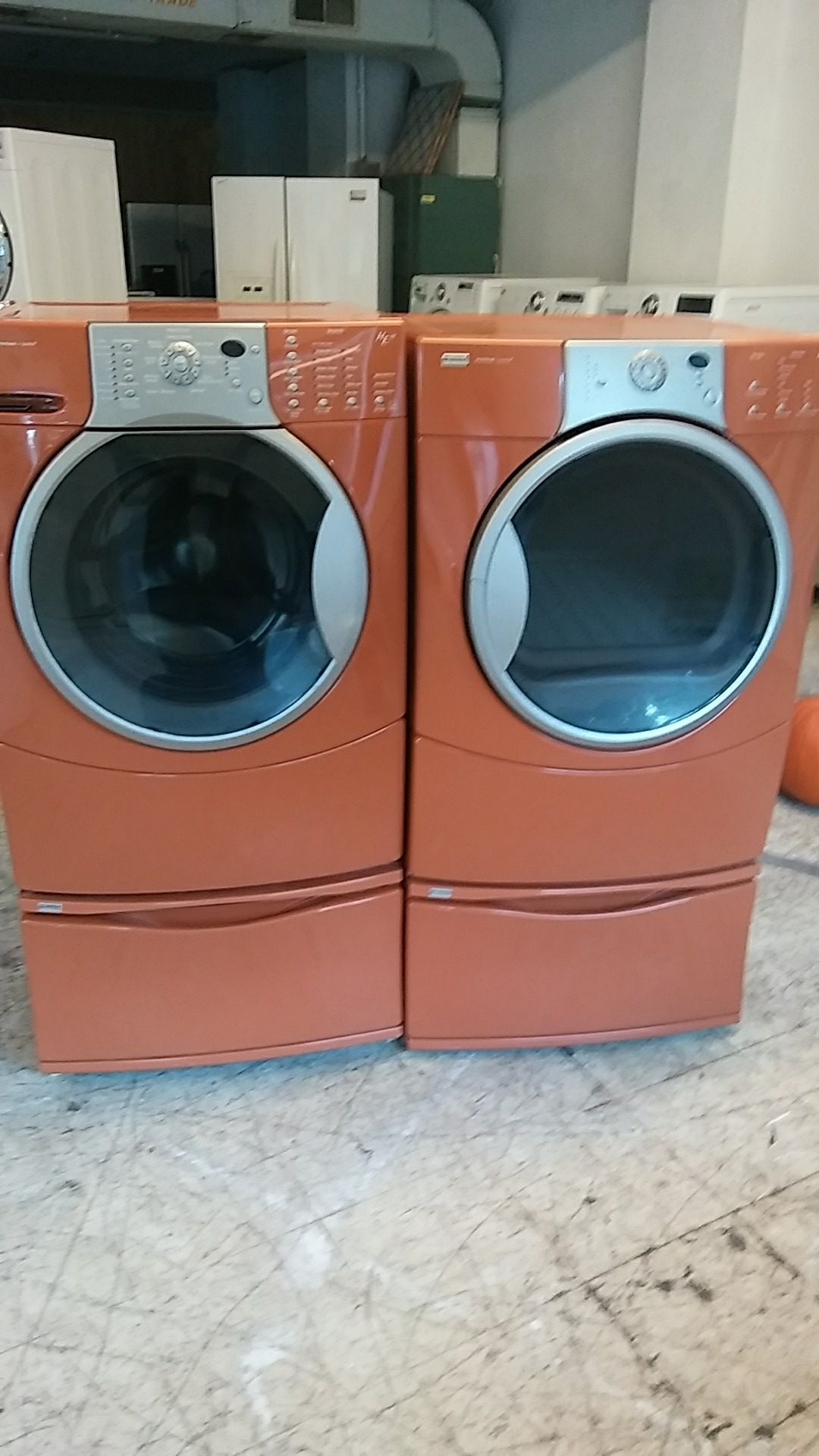 Orange Kenmore Elite frontload washer, and dryer set on pedestals.
