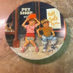 This item is a 1982 vintage collector plate titled "The Pet Shop," featuring artwork by Mike Hagel. It is part of "The Children's Hour" series produce