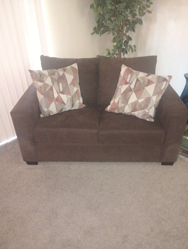 Brown Sofa Chair With Two Multi Colored Pillows