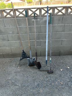 Two shovels a metal rake, a hula hole and a leave rake