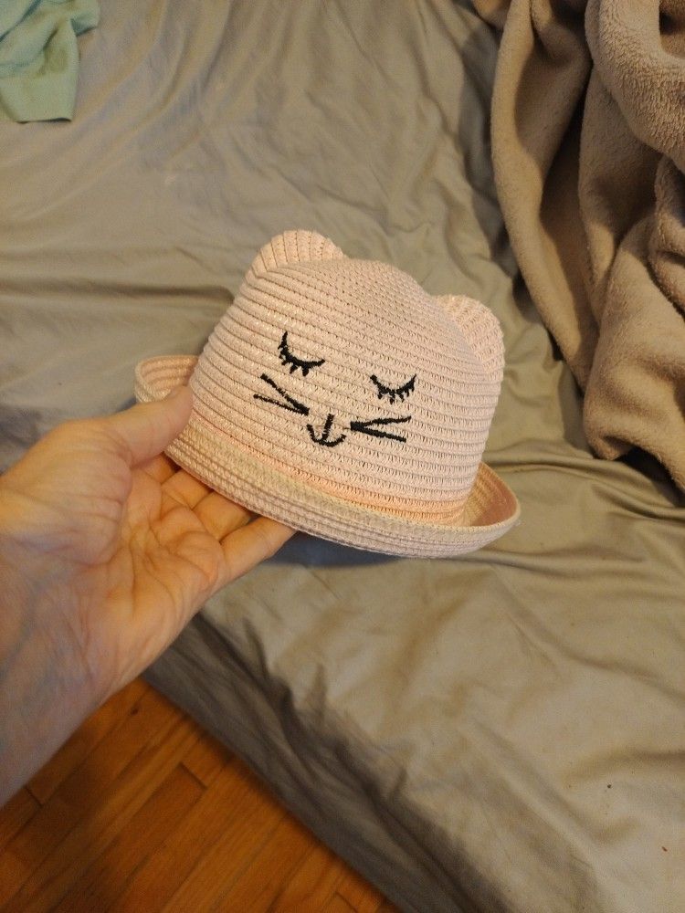 A Pink Straw Hat With Animal Face Highlighted In Black It Also Has Two Ears