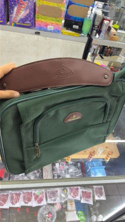 green Samsonite travel bag features a prominent brown leather shoulder strap and a classic gold-tone brand logo