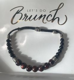 A red tiger’s eye, onyx, and silver beaded bolo bracelet. 