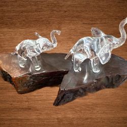 Clear glass decorative elephant on a wooden base, with its trunks raised for good luck