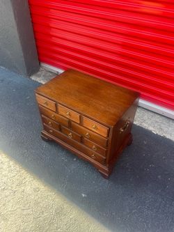 vintage wooden silver chest featuring brass side carrying handles and multiple small drawers.