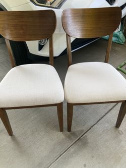 Two wood chairs with off-white cushions