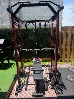 Mikolo Gym squat rack w weights and a leg machine.