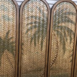 vintage coastal-style woven rattan folding screen or room divider with a palm tree pattern. 