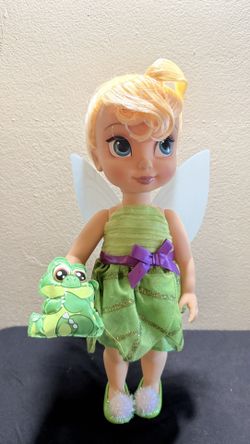 Tinker Bell is outfitted in a green satin dress with petal skirt overlay Sateen bodice with pleated organza overlay Contrast satin ribbon with bow at