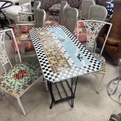mosaic-topped table features a checkered border and wrought iron legs with pair of chairs