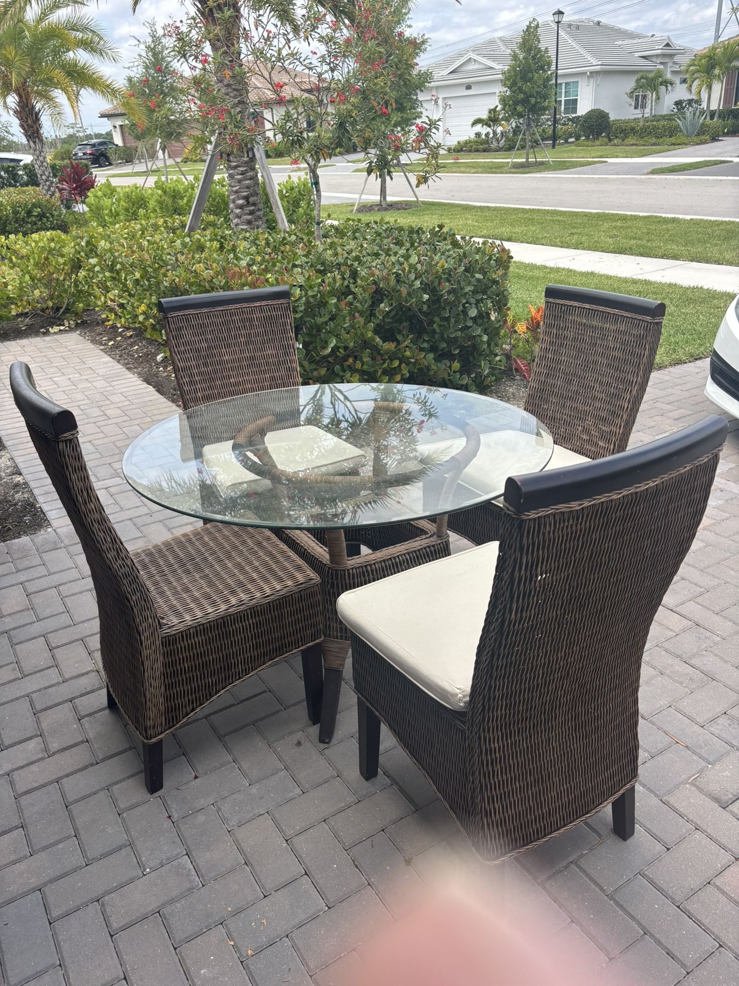 Round Glass Table With Four Wicker Chairs and Cushions