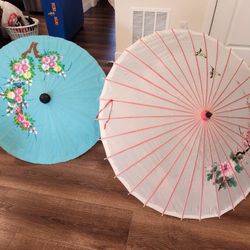 2 Asian parasols made of bamboo and fabric, hand-painted with floral and birds, primarily used for sun protection or decoration. 