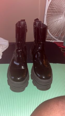 These black patent leather mid-calf boots feature a thick, chunky platform sole and a side zipper closure