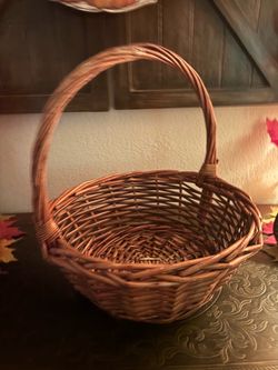 round, hand-woven brown wicker gathering basket with a single arched overhandle