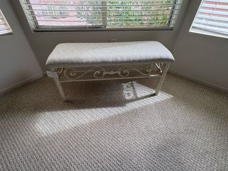 This is a white wrought iron vanity or bedroom bench featuring scrollwork details