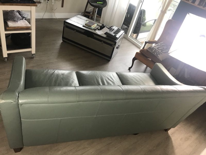 Mint tufted leather couch and solid wood chest