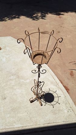 decorative wrought iron plant stand features a gold-toned finish and scrollwork details
