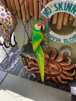 Large colorful carved wooden parrot on a swing