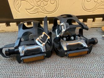 This is a pair of 9/16-inch bicycle pedals featuring black toe clips and adjustable straps