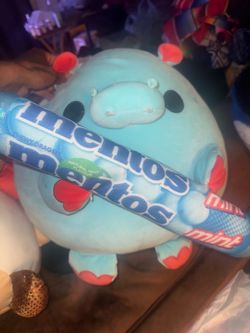 a blue hippo holding a Mentos mint snack