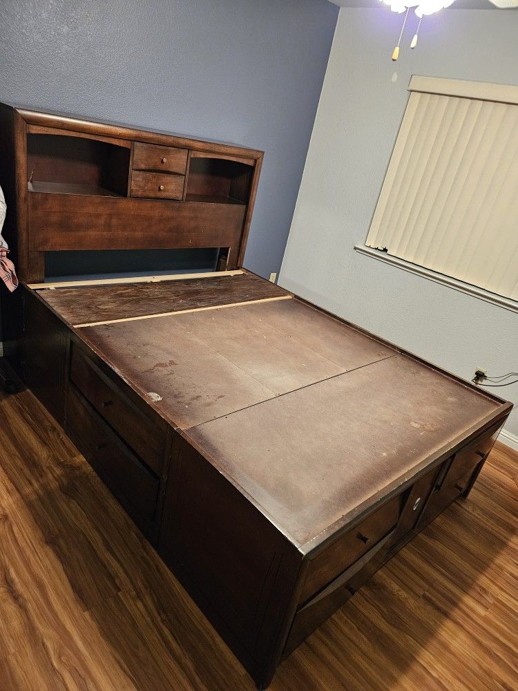 wooden queen-size captain's bed with a bookcase headboard and storage drawers.