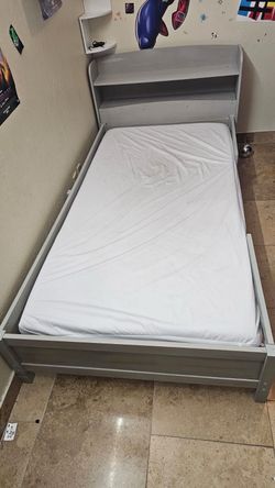 Gray twin bed with mattress
