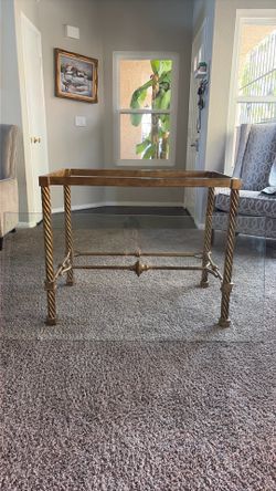 Hollywood Regency-style metal and glass console table featuring a distinct antiqued  gold or brass finish